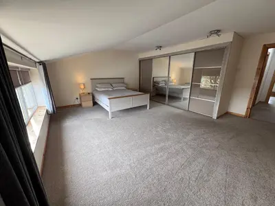 a large bedroom with a bed and a bathroom at Langside apartments in Newhouse
