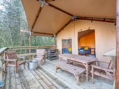 a tent with picnic tables and chairs on a deck at Cobleland Campsite in Gartmore
