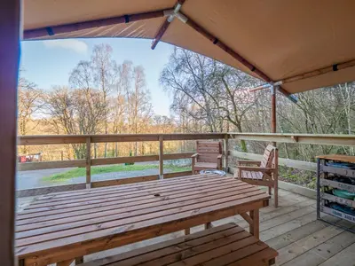 a wooden bench on a deck with a tent at Cobleland Campsite in Gartmore