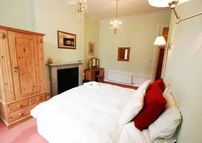 a bedroom with a white bed and a fireplace at Edlets - Frederick Street Apartment in Edinburgh
