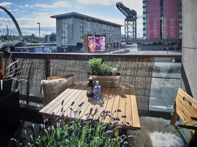 a wooden table sitting on top of a balcony at Glasgow, Finnieston Luxury 2 Bed with parking, e-check in, hi-fi in Glasgow