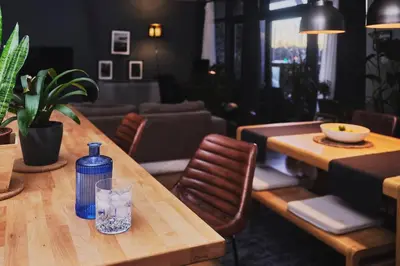 a wooden table with a bottle and a glass on it at Glasgow, Finnieston Luxury 2 Bed with parking, e-check in, hi-fi in Glasgow