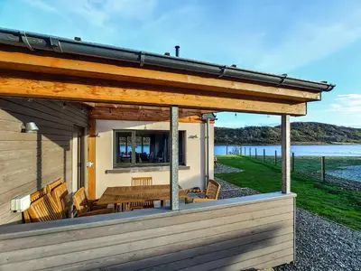 a house with a deck with a table and chairs at Tulamain in Ardfern