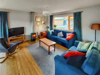 a living room with two blue couches and a television at Tulamain in Ardfern