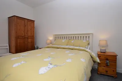a bedroom with a yellow bed with white birds on it at Heronlea Cottage in Dunoon