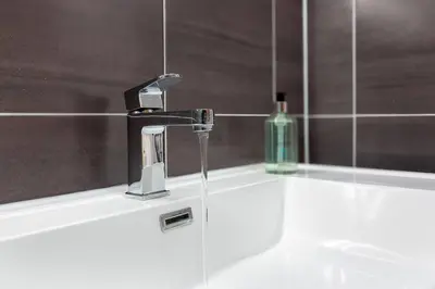 a bathroom sink with a faucet and a bottle of soap at The Stylish 3-Bedroom Maisonette Retreat in Stirling