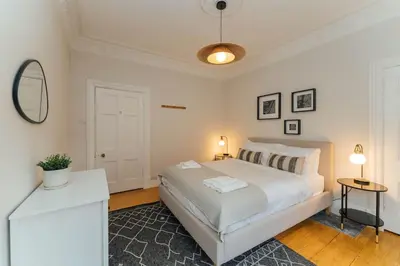 a white bedroom with a bed and a mirror at James Street 2 Bedroom Apartment in Stirling