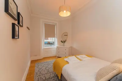a small bedroom with a bed and a mirror at James Street 2 Bedroom Apartment in Stirling
