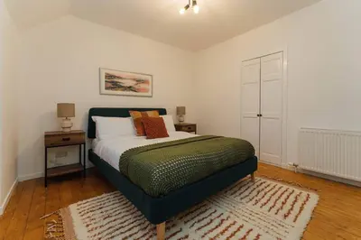 a bedroom with a bed and two tables and a door at The Old Deanston Workers Cottage in Doune