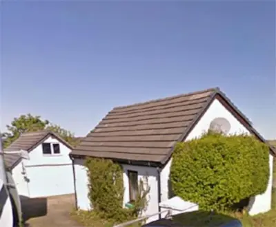 a white house with a large bush in front of it at Rhumhor in Bunessan