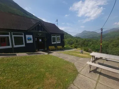 a black building with a bench in front of it at West Highland Lodge in Kinlochleven