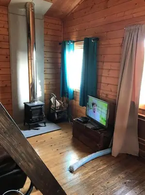 a living room with a tv on a wooden wall at Ardchiavaig Cabin in Uisken