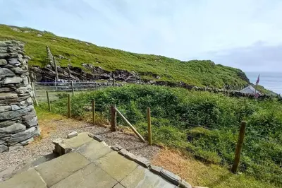 a fence on the side of a hill near the ocean at Ardchiavaig Cabin in Uisken