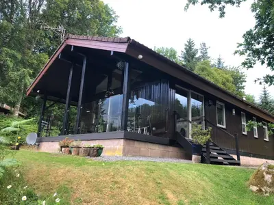 a house with a glass facade on a lawn at Sixpenny Bay in Morenish