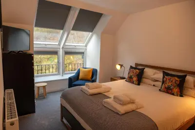 a bedroom with a bed and a tv and a chair at Cairn Cottage in Onich