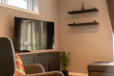 a living room with a large flat screen tv at Cairn Cottage in Onich