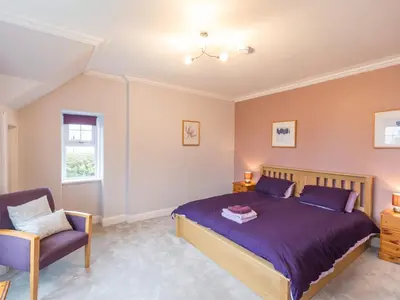 a bedroom with a bed and a chair at 5 Bed in Brodick CA016 in Brodick