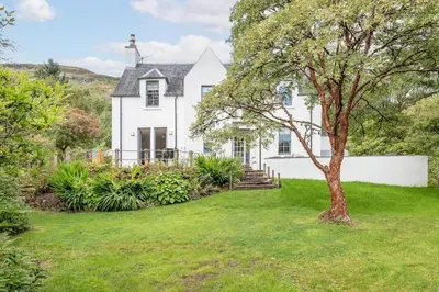 a white house with a tree in the yard at Stunning Dalchenna w/hot tub & huge garden in Stirling
