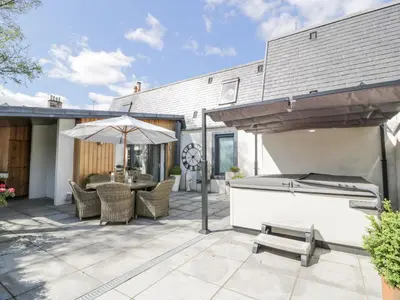 a patio with a grill and an umbrella at Shepherdess Cottage in Moffat