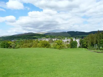 a green field with a town in the distance at Shepherdess Cottage in Moffat