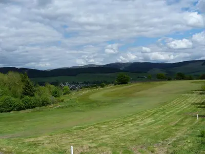 a view of a golf course with mountains in the background at Shepherdess Cottage in Moffat