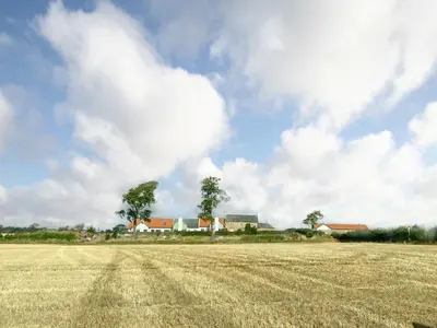 a field of dry grass with houses in the background at The Old Mill in Linlithgow