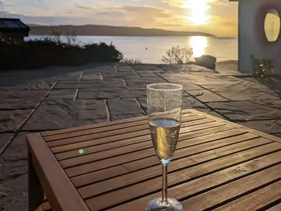 a glass of champagne sitting on a wooden table at Shore House in Kilcreggan