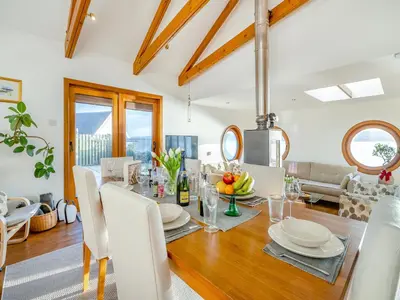 a dining room with a table with white chairs at Shore House in Kilcreggan