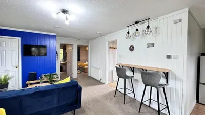 a living room with a blue accent wall and a blue couch at Whisky Whispers Hunters Quay in Sandbank