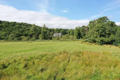 a field of grass with a house in the background at Tarbert Country Manor in Tarbert