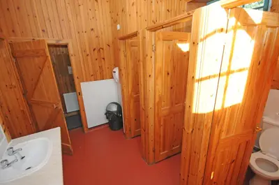 a bathroom with wooden walls and a sink and a toilet at Blackwater Glamping Pods in Kinlochleven