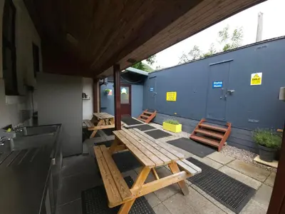 a patio with wooden benches and a blue wall at Blackwater Glamping Pods in Kinlochleven