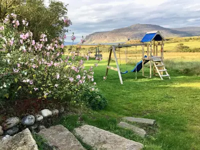 a playground in a field with a hill in the background at Bremenvoir Barn in Bunessan