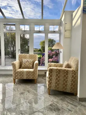 a living room with two chairs and a large window at Bremenvoir Barn in Bunessan
