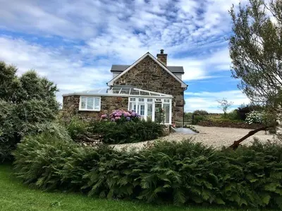 a stone house with white windows and flowers at Bremenvoir Barn in Bunessan