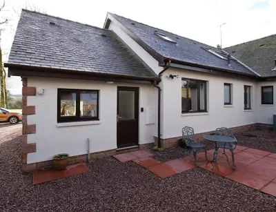 a white house with a patio and a table at Hollys Hideaway in Castle Douglas