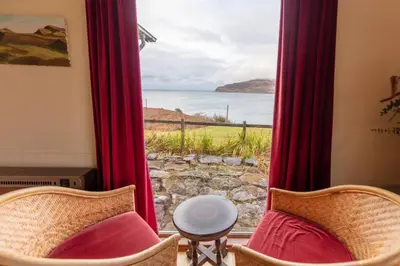 a room with a window with a view of the ocean at Ormsaig Wooden Cottage in Burgh
