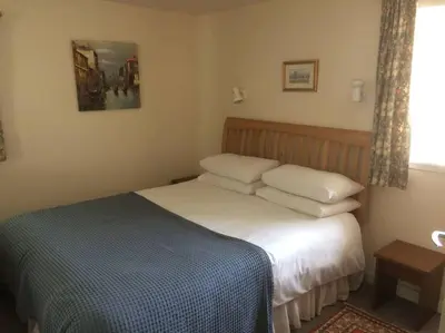 a bedroom with a bed with a blue and white blanket at Stable Cottage, Ardnadrochet in Lochdon