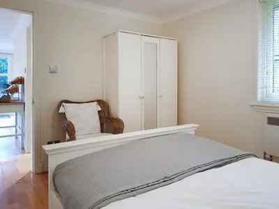 a bedroom with a bed with a chair and a cabinet at Leven Lodge 3 - Uk46045 in Balloch