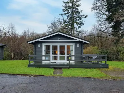 a small house with a bench in the grass at Leven Lodge 3 - Uk46045 in Balloch