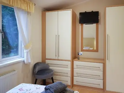 a bedroom with a bed and a cabinet and a chair at Kingfisher Lodge - Uk46046 in Balloch