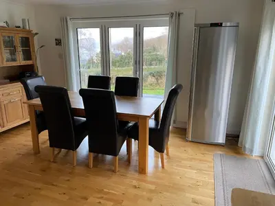 a dining room table with chairs and a refrigerator at The Cottage, overlooking Loch Fyne in Cairndow