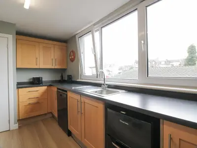 a kitchen with wooden cabinets and a sink and a window at Little Ireland in Stranraer