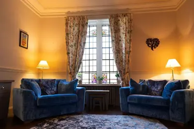 a living room with two blue chairs and a window at Saskatchewan House in Oban