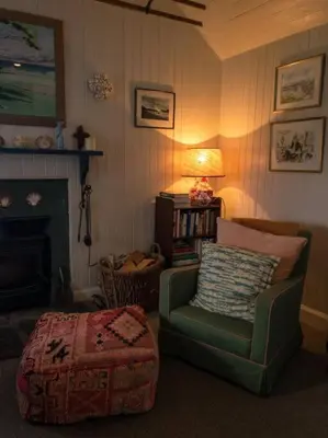 a living room with a green chair and a lamp at Archie's Cottage in Auchnacraig
