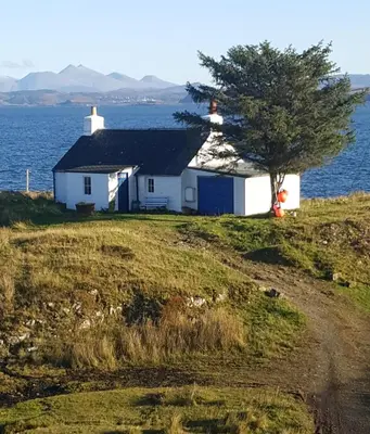 a house on the side of a hill with a tree at Archie's Cottage in Auchnacraig