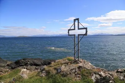 a cross on the side of a hill near the water at Archie's Cottage in Auchnacraig