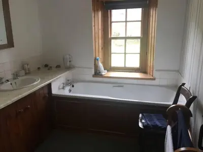 a bathroom with a tub and a sink and a window at Barrachandroman Farmhouse in Lochbuie