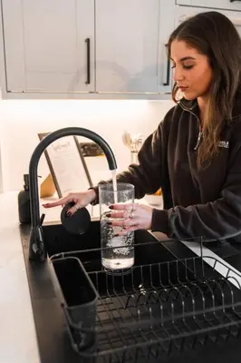 a woman is pouring a drink into a glass at The West End Retreat - Your Luxurious 5* Apartment in Glasgow
