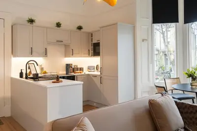 a kitchen with white cabinets and a couch in a room at The West End Retreat - Your Luxurious 5* Apartment in Glasgow